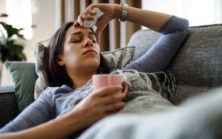 Sick woman lying on couch, eyes closed