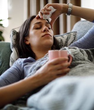 Sick woman lying on couch, eyes closed