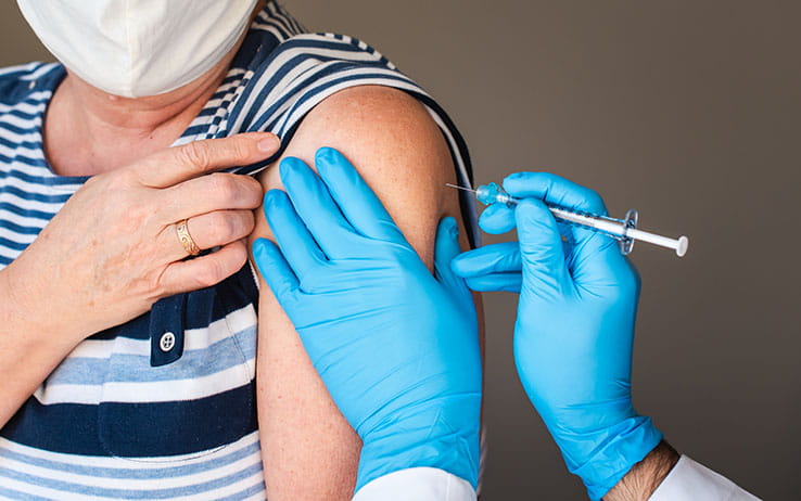 Masked female receiving a flu shot in the arm