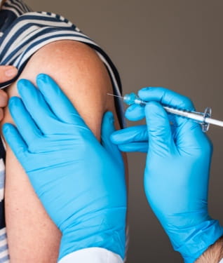 Masked female receiving a flu shot in the arm