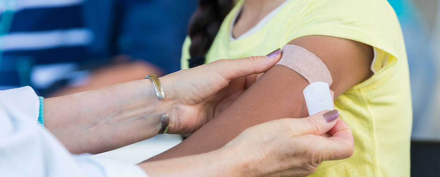 Female clinician placing a bandage on woman's arm after a flu shot